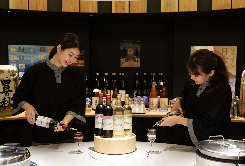 島根のワイナリーが醸造した赤・白ワイン「葡萄神話」をワイングラスに注ぐ女性