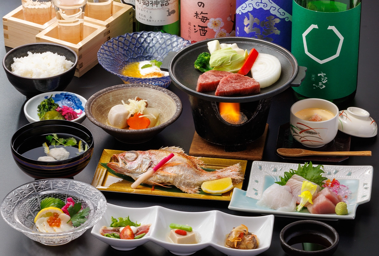 色とりどりの器に盛られた豪華なお料理。前菜、のどぐろの煮つけ、お刺身、茶碗蒸し、厚切りの牛肉を味わえる「四季創作会席 (グレードアップ)」