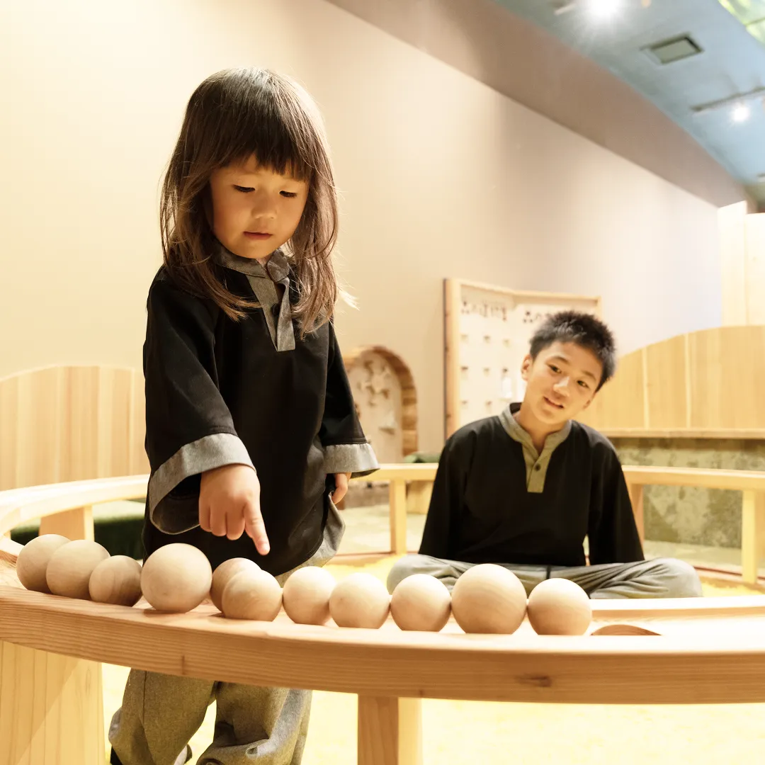 木製のボールころがしプールで遊ぶこどもたち