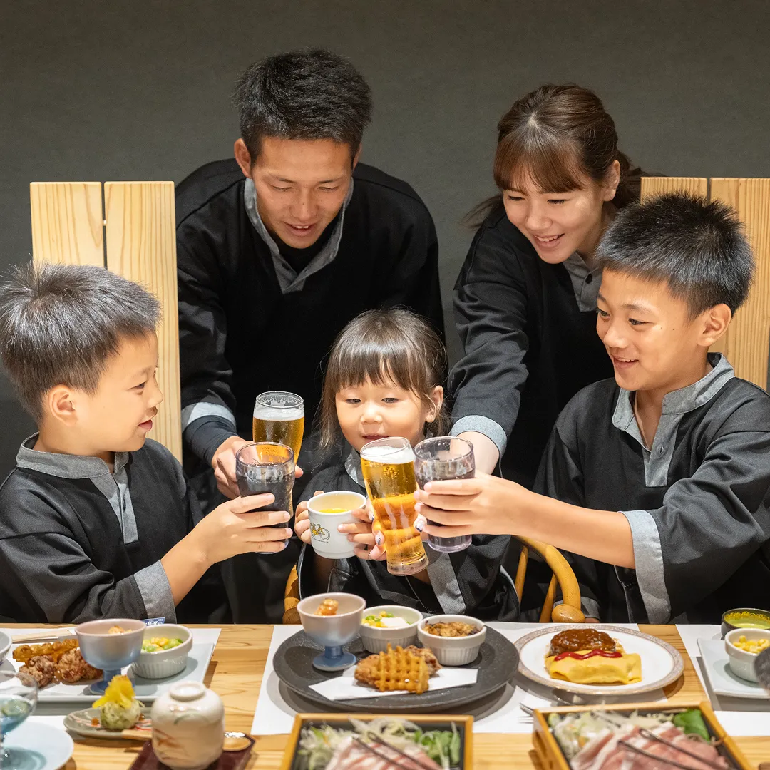 お子様料理を前にフリードリンクで乾杯する笑顔のご家族
