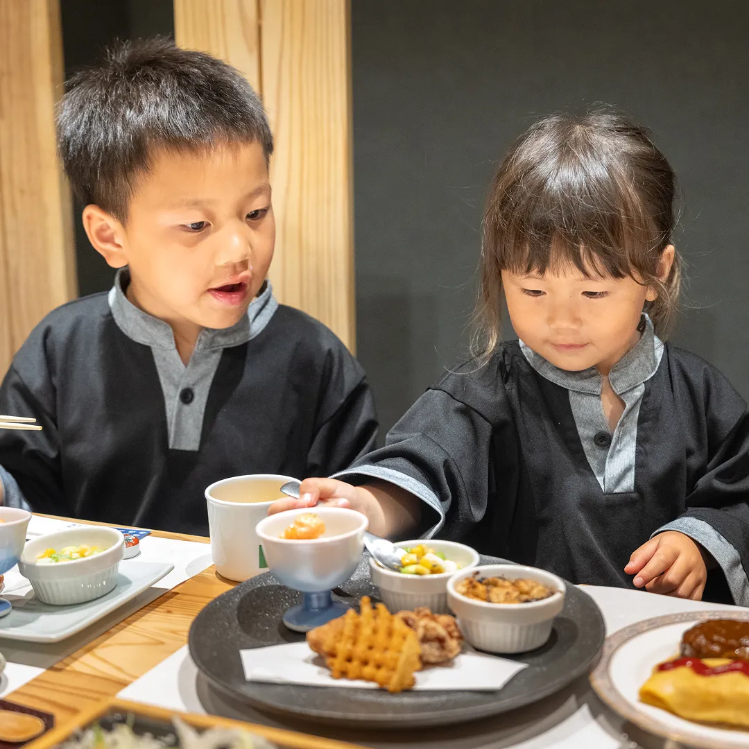 一生懸命お子様料理を食べる女の子とそれを見守る男の子