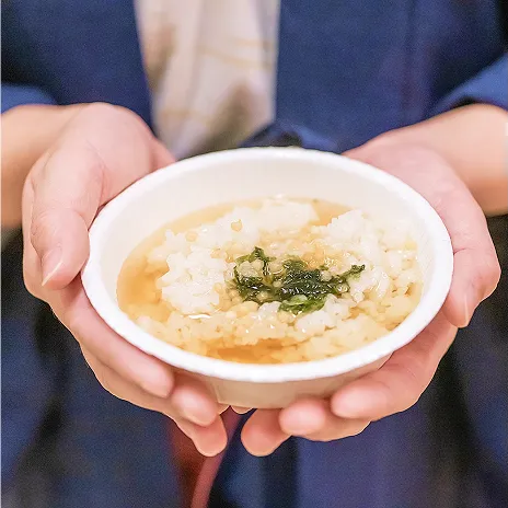 温かいだしが注がれたお茶漬けを、両手で包み込むように持つ様子。