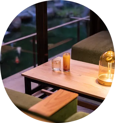 バーラウンジの画像です。窓の外に庭園が見える席に、飲み物が入ったグラスが2つ置かれています。おしゃれな照明が灯り、落ち着いてゆったりと過ごせる雰囲気が伝わってきます。