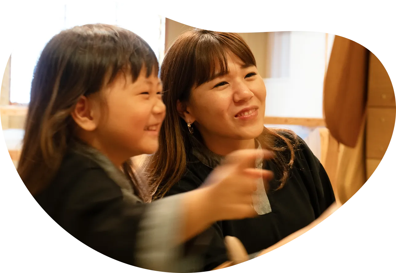 親が子どもと笑顔で会話している画像です。母親らしき女性が優しく微笑みかけ、子どもが何かを指差しながら嬉しそうに笑っています。家族の温かく和やかな雰囲気が伝わってきます。
