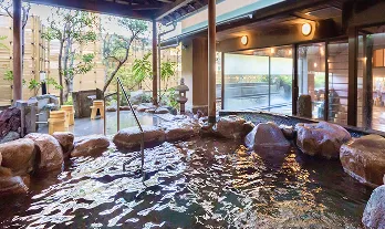 木のぬくもりを感じる屋根の下、岩風呂に身を浸す贅沢な時間。湯気が立ち上り、心も体も温まります。