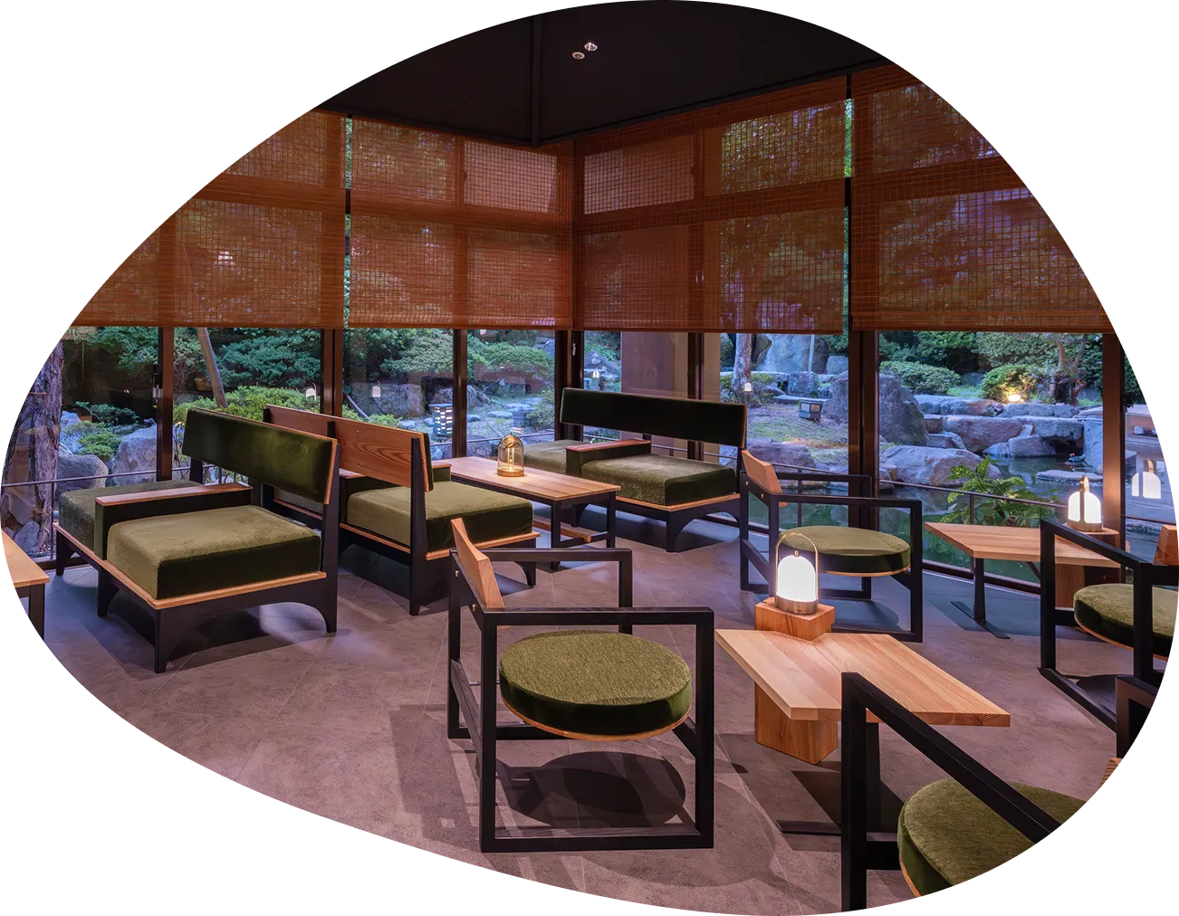 和風庭園に面したバーラウンジの画像です。大きな窓の外にはライトアップされた庭園が見え、シックな色合いのソファや椅子、テーブルが配置されています。間接照明の温かい光が、落ち着いた大人の時間を演出している様子が伝わってきます。