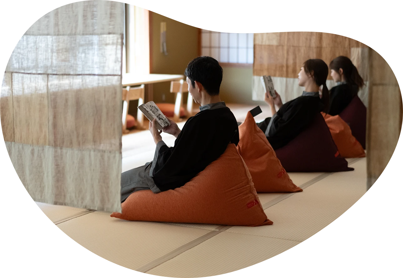 OQOQの湯上りどころ。畳とクッションでリラックスしながら読書を楽しむ男女