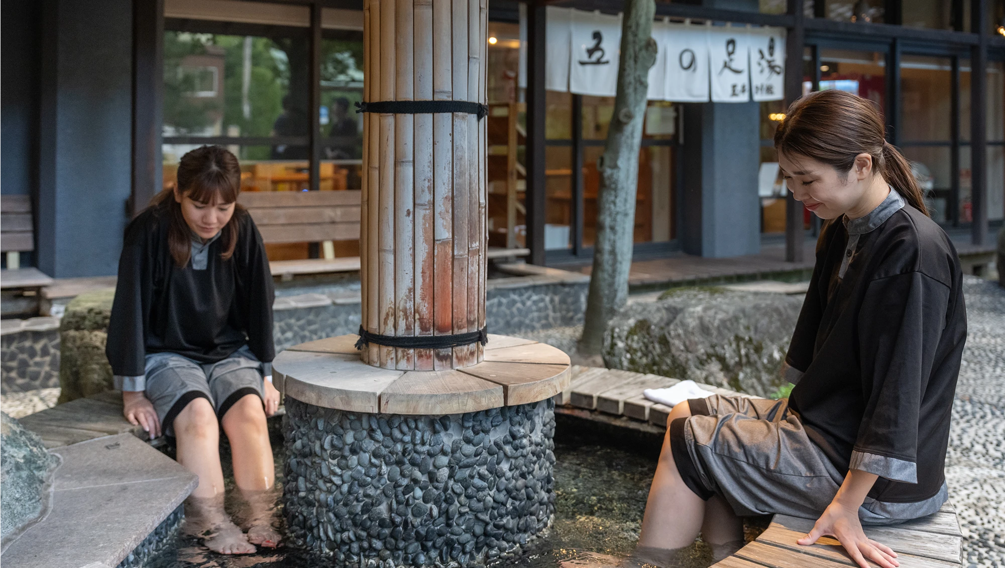 作務衣でOQOQの足湯を楽しむ女性